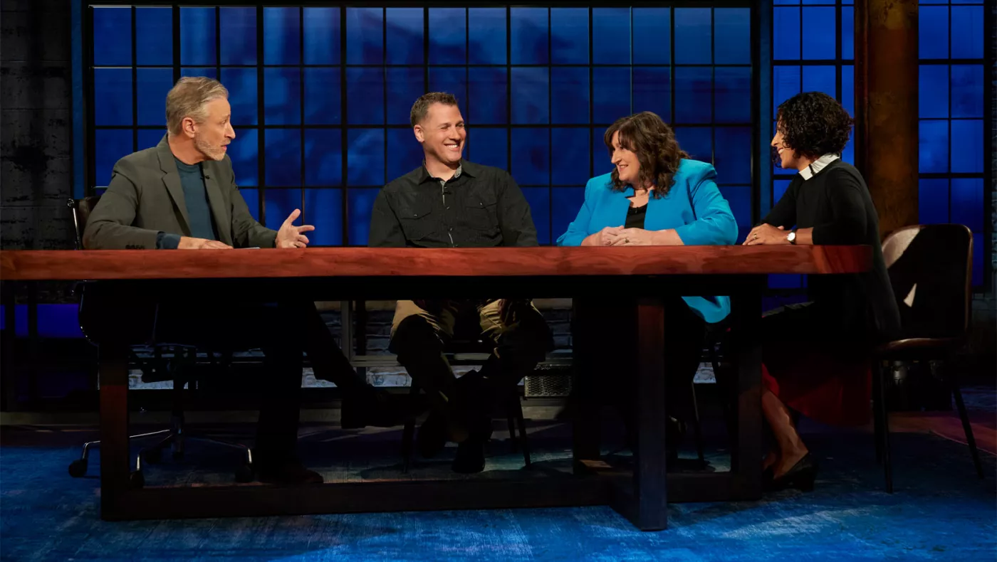 A shot from the set of "The Problem with Jon Stewart" showing Jon Stewart, and 3 guests, including The SCEA President Sherry East in a blue coat.