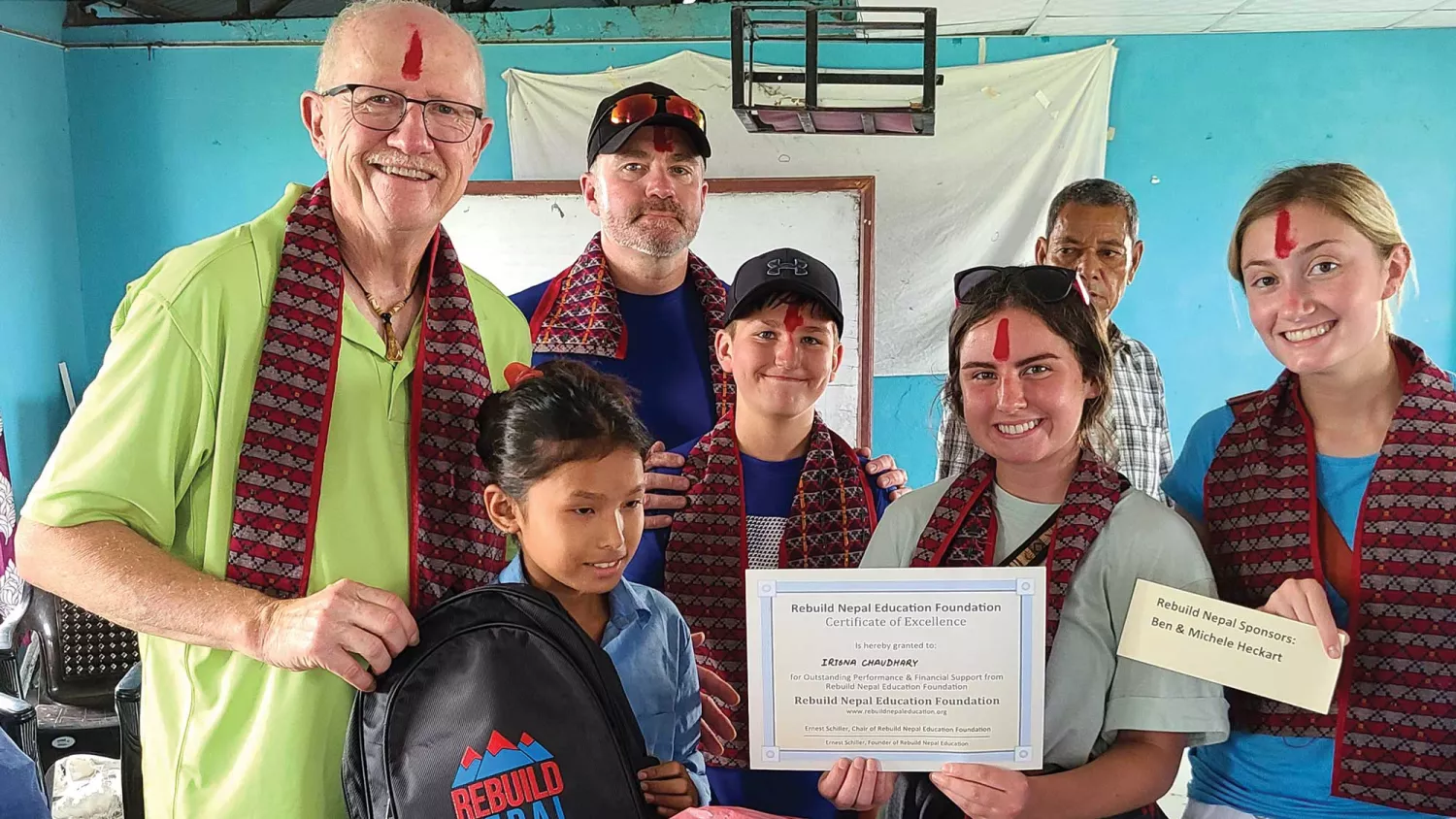 Ernie Schiller and other volunteers present a scholarship to a Nepali student. The locals painted red tikas on their foreheads, which symbolize goodness.