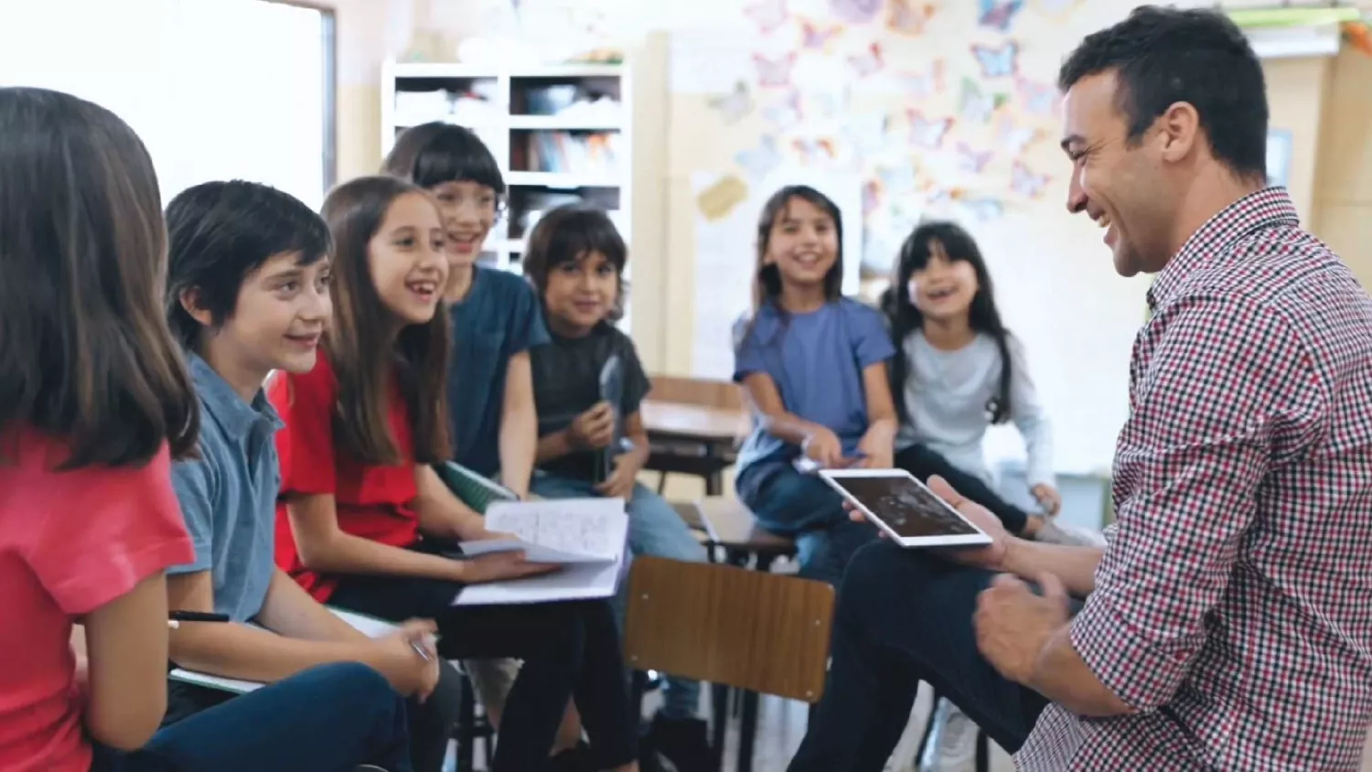 Caucasian Male teacher with students smiling.