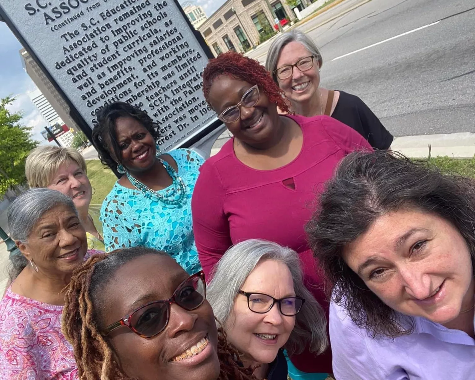 The SCEA-Retired members and active members stand in front of a roadmarker about the merger of PEA & SCEA.