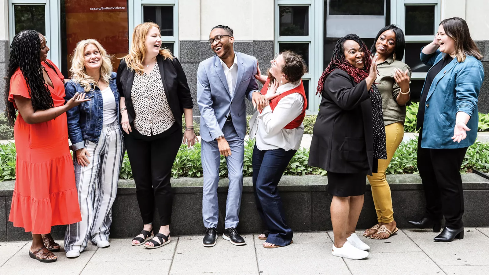Nine educators stand outside the NEA headquarters building in Washington, DC talking