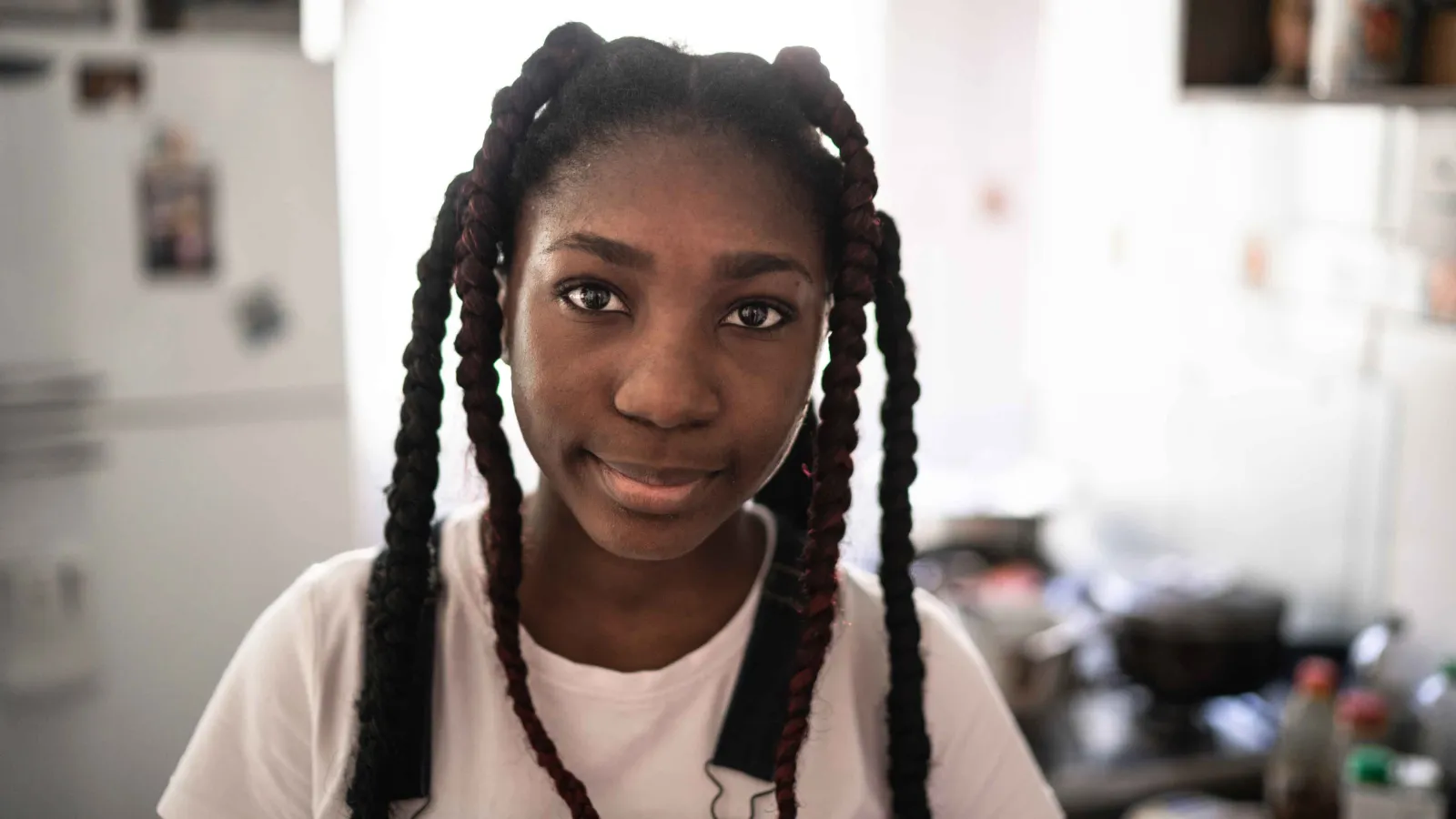 A black teenage girl with braids smiles