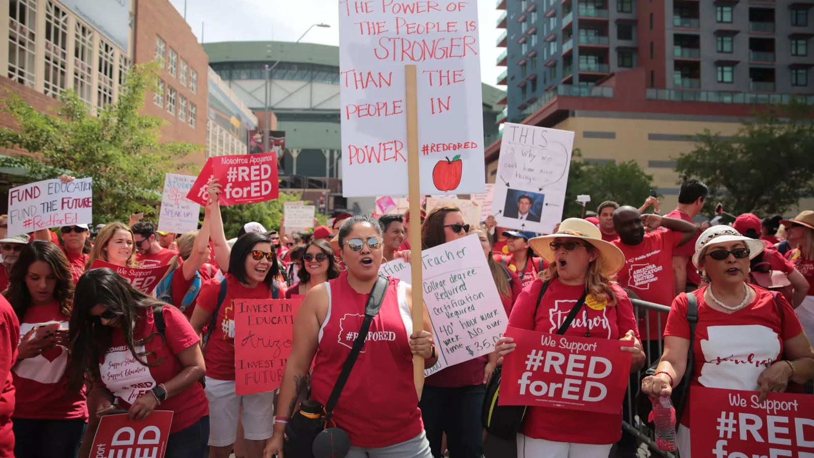 Women wearing red shirts, holding picket signs