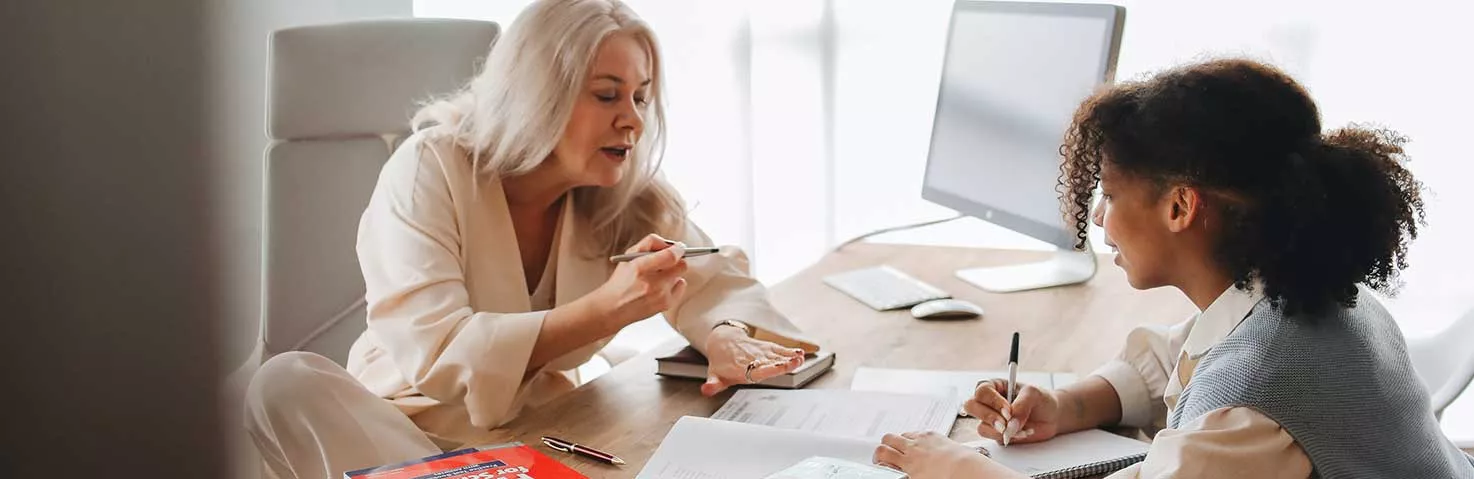Older educator with student at desk