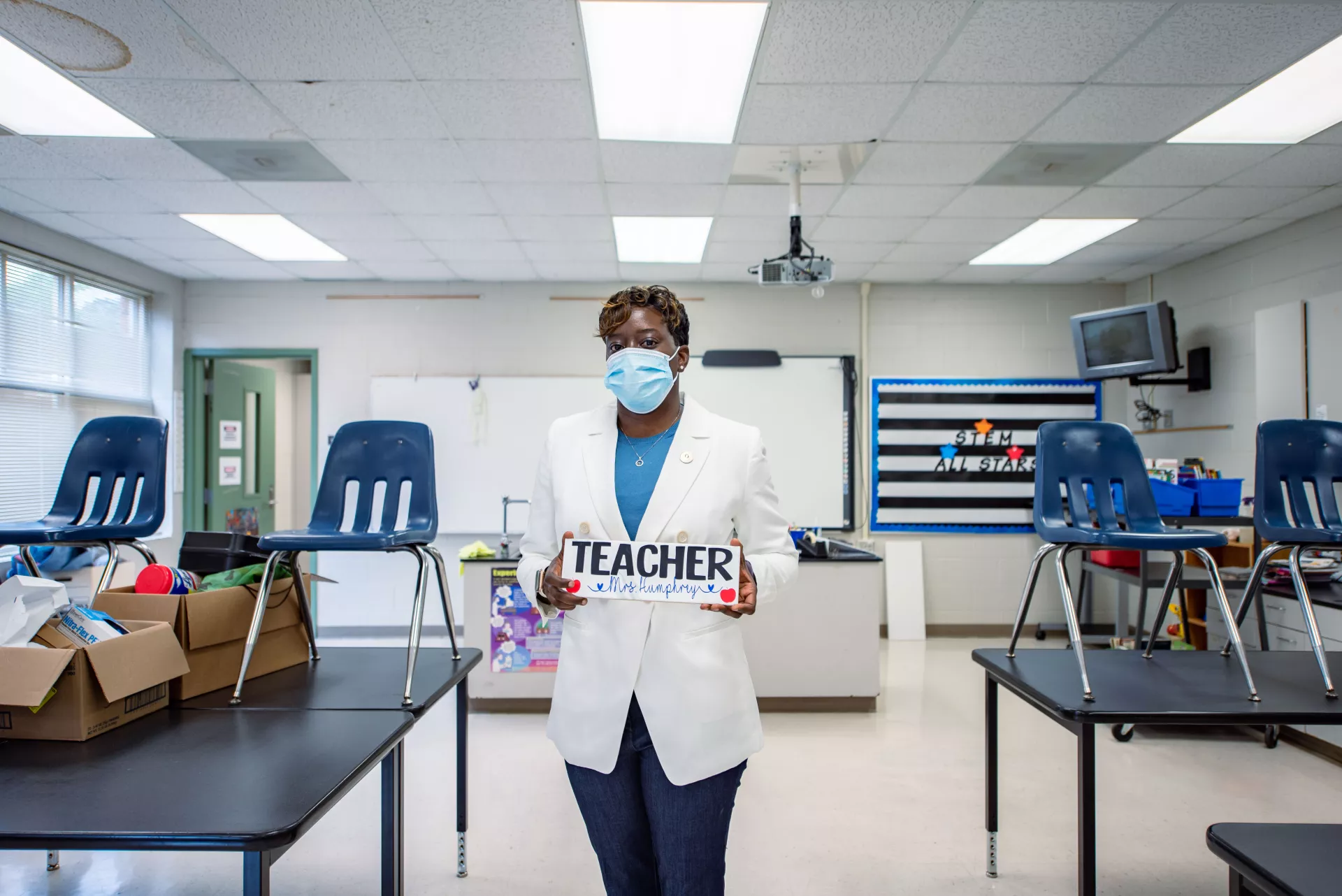 A teacher stands in her classroom packed for the year.