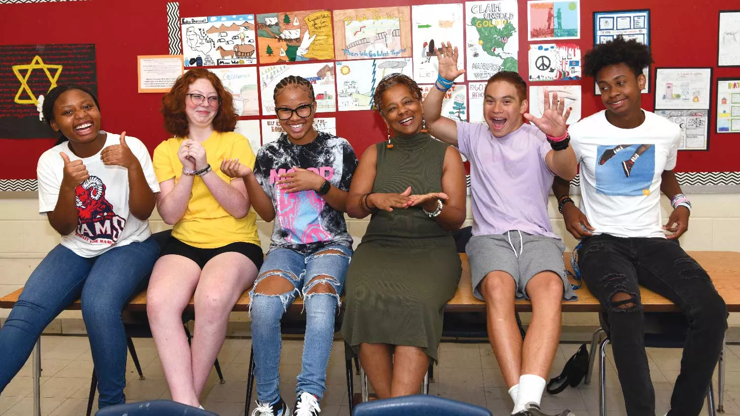 Maryland English teacher Ann-Marie Maloney, here with a few of her middle school students smiling while sitting in front of their artwork.