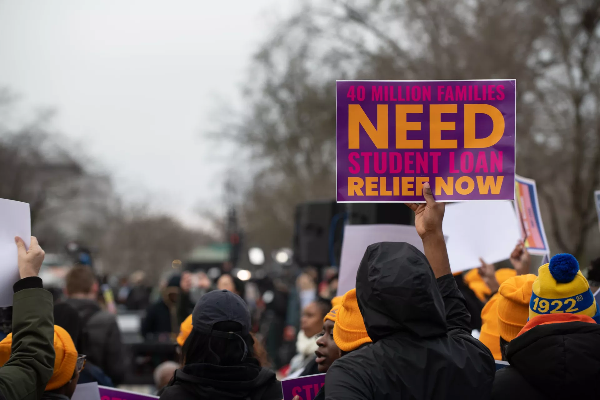 Sign held up at rally saying 40 million families need student loan relief now.