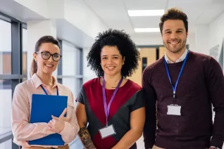 three educators in a school hallway, two women and one man.