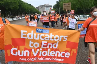 Educators march with a banner that says "Educators to end gun violence"