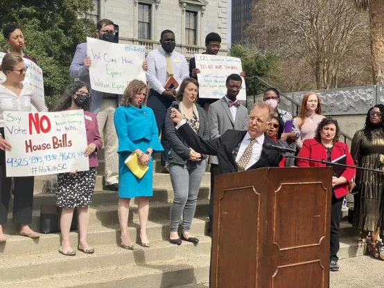 Legislators, ProTruth coalition members, and The SCEA President and members stand up a the ProTruth Press Conference. They hold signs urging legislators not to pass legislation that limits the history our students can learn.
