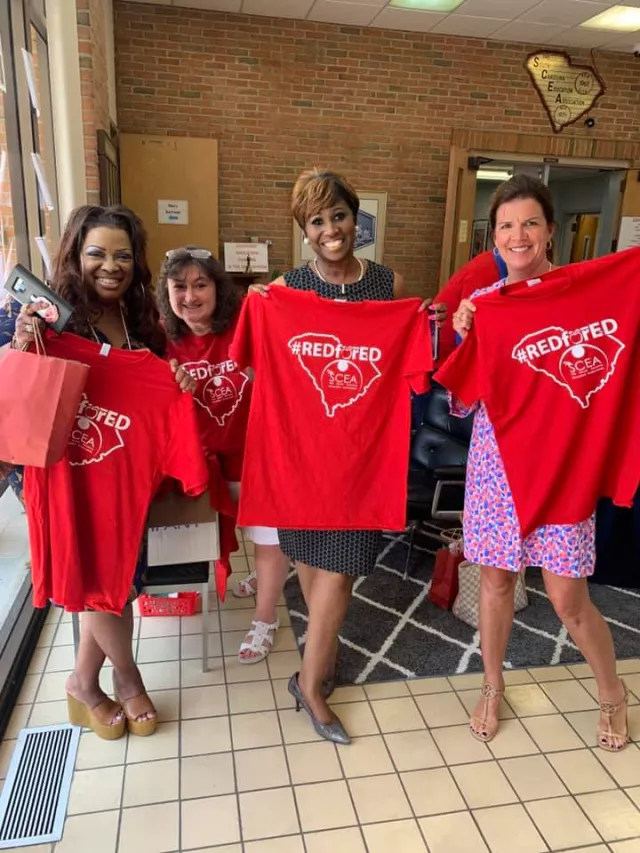 Members pose with Red for Ed shirts.