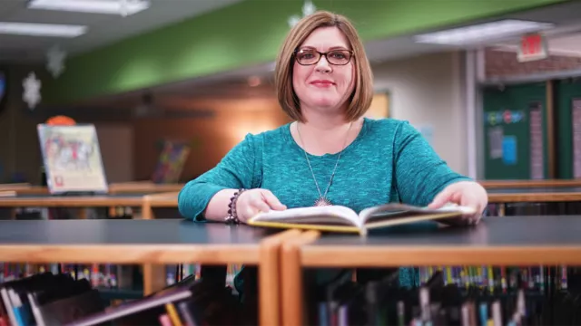 female librarian posing near bookshelf in the library