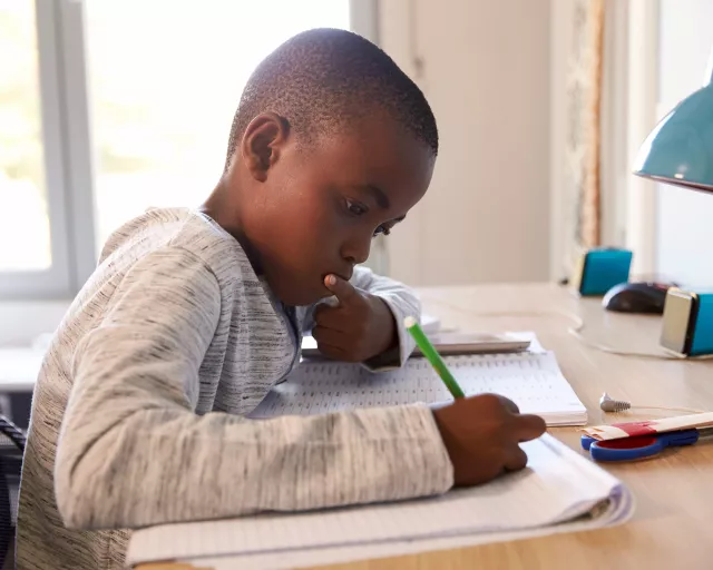 young boy writing at his desk at home
