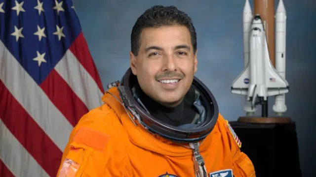 Astronaut Jose Hernandez in his orange space suit posing for an official portrait
