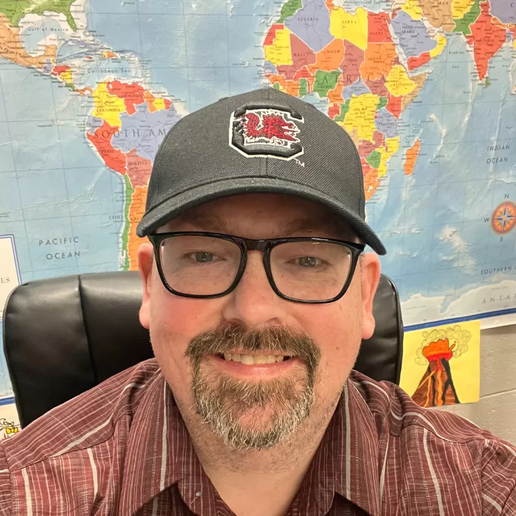 Charles Dickson poses for a selfie at his desk.