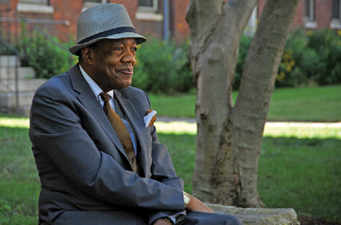 A profile view of Walter Harper wearing a suit, sitting on a bench.